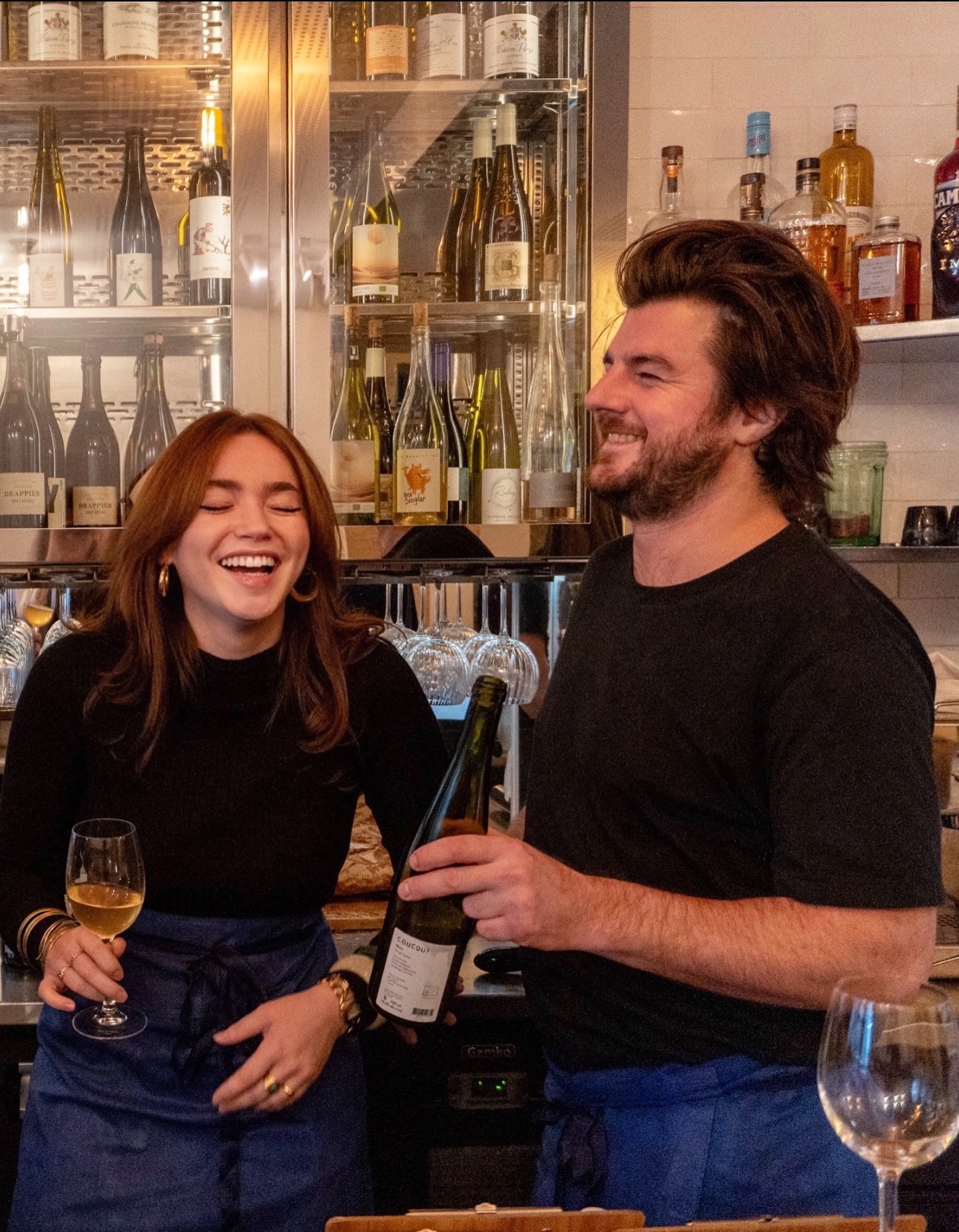 L'équipe derrière le comptoir, verres de vin à la main